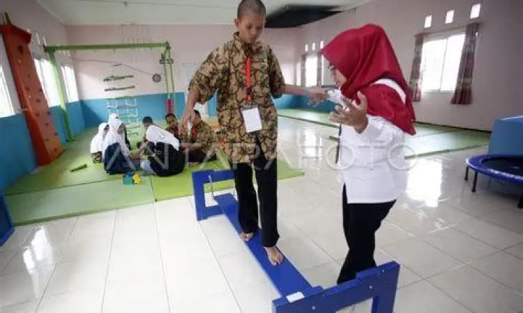 Terapis sedang membantu anak tuna grahita