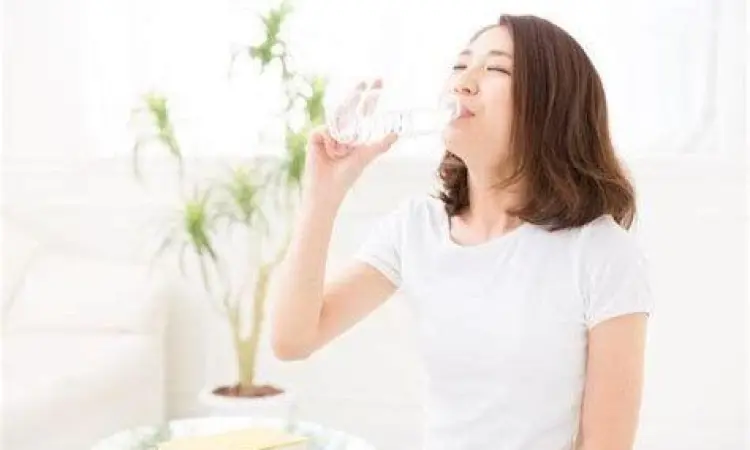 Seseorang memegang segelas air putih untuk membantu pemulihan batuk