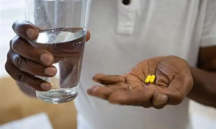 Seseorang sedang minum obat dengan segelas air