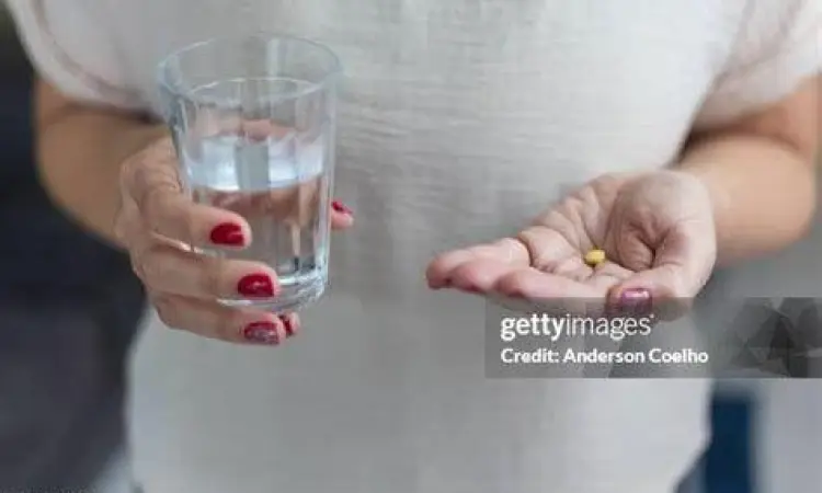 Seseorang meminum pil dengan segelas air